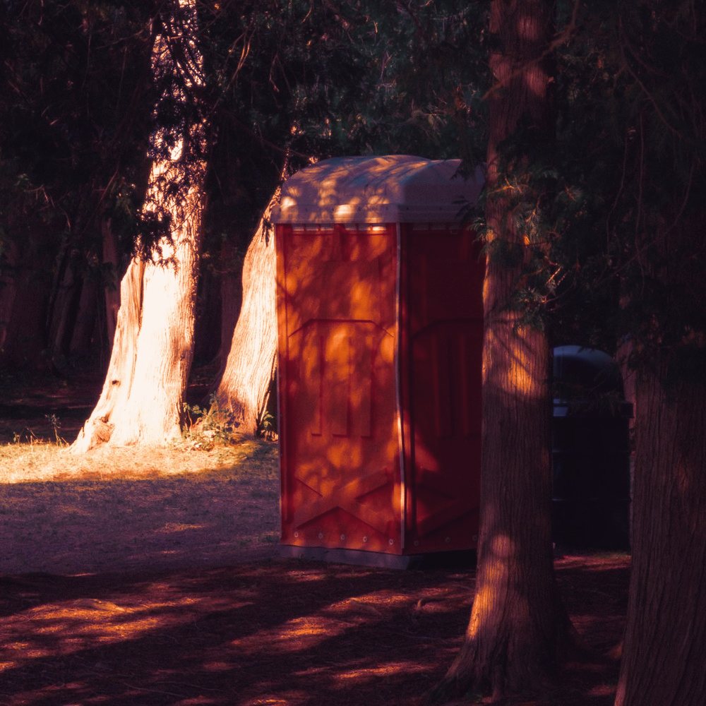 Cabine sanitaire mobile posée en lisière de forêt, à l'écart de tout raccordement